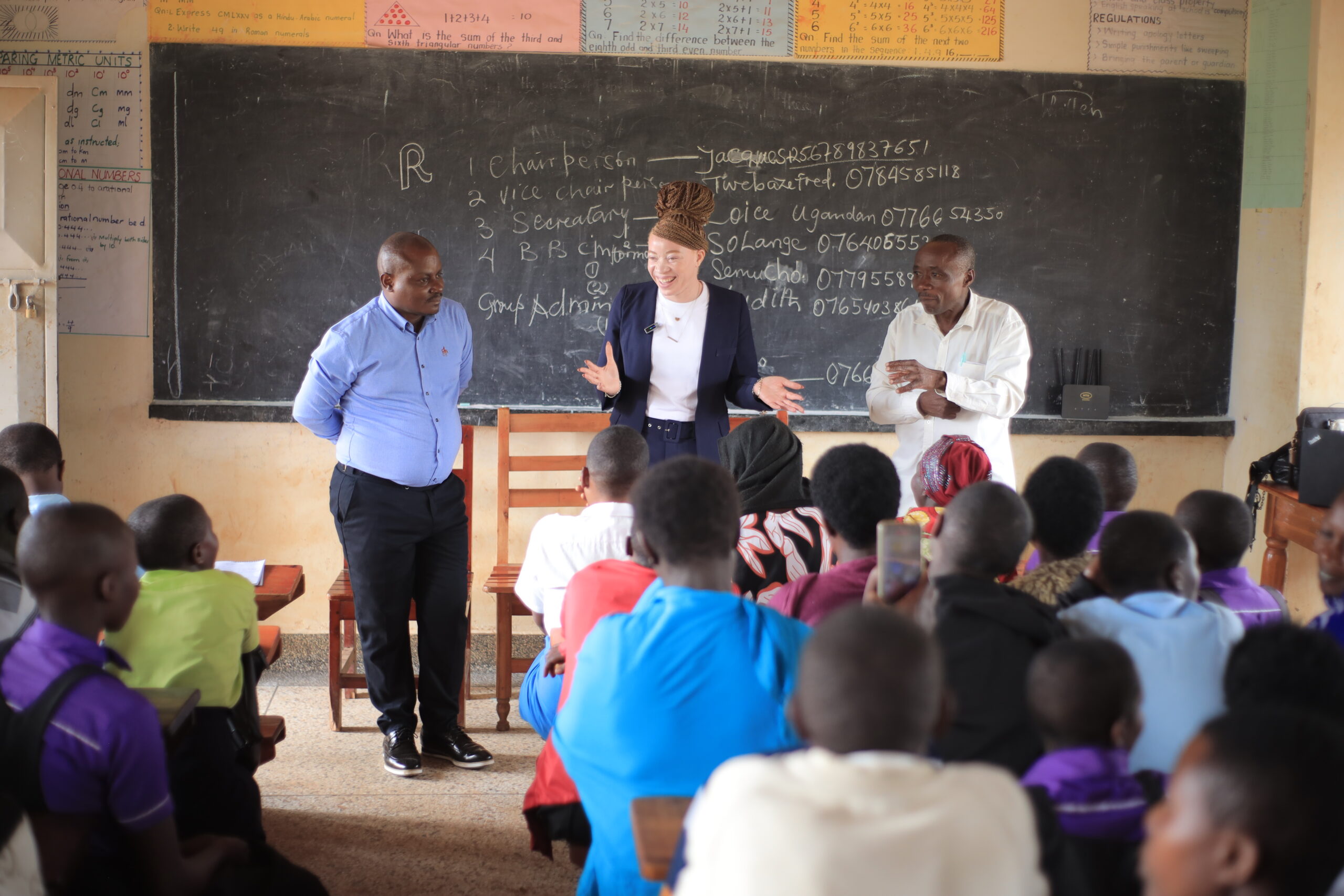 Chantale standing and speaking to the children and their parents in front of a blackboard